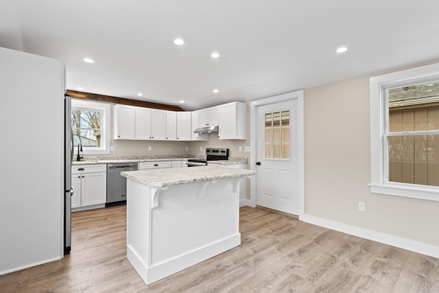 kitchen featuring white cabinets, appliances with stainless steel finishes, light wood-style floors, baseboards, and under cabinet range hood