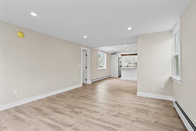 unfurnished living room with recessed lighting, light wood-style floors, and a baseboard heating unit