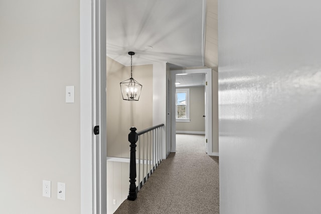 corridor with carpet floors, baseboards, and a chandelier