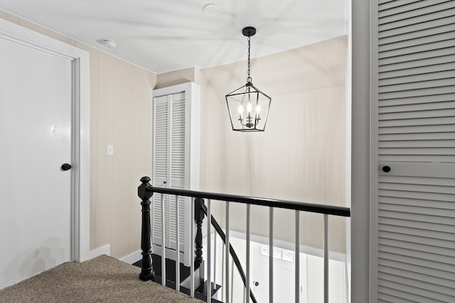 stairs featuring carpet flooring and a notable chandelier
