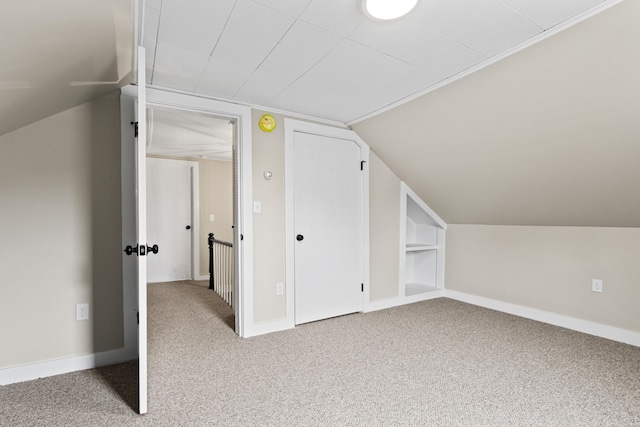 bonus room with baseboards, carpet flooring, built in shelves, and lofted ceiling