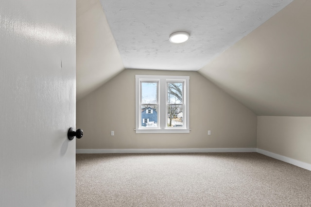 additional living space with carpet flooring, baseboards, and vaulted ceiling