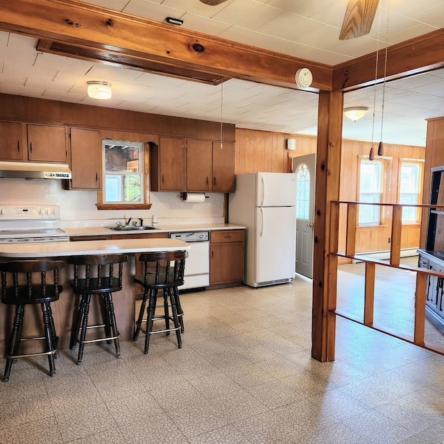 34 Chase Ave, Mexico, ME 04257 - kitchen with white appliances, under cabinet range hood, light flooring, wooden walls, and light countertops