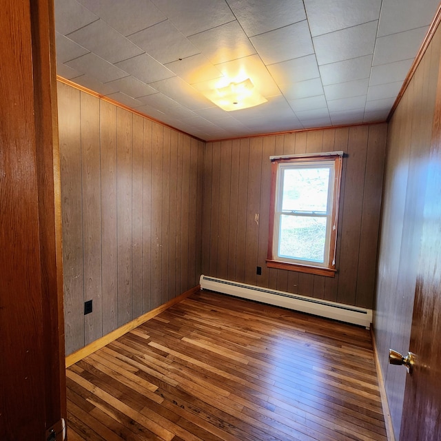 34 Chase Ave, Mexico, ME 04257 - spare room featuring baseboard heating, hardwood / wood-style flooring, wood walls, and baseboards
