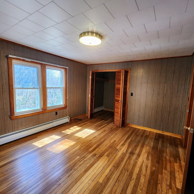 34 Chase Ave, Mexico, ME 04257 - unfurnished bedroom featuring a baseboard heating unit, hardwood / wood-style flooring, wood walls, and a closet