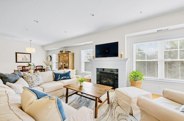 75 Clearwater Dr Unit 305, Falmouth, ME 04105 - living room with visible vents, a glass covered fireplace, a wealth of natural light, and wood finished floors