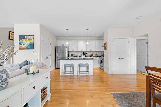 75 Clearwater Dr Unit 305, Falmouth, ME 04105 - kitchen featuring dark countertops, appliances with stainless steel finishes, white cabinets, light wood finished floors, and open floor plan