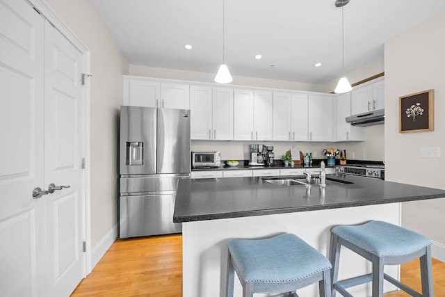 75 Clearwater Dr Unit 305, Falmouth, ME 04105 - kitchen featuring dark countertops, a sink, stainless steel appliances, a kitchen bar, and under cabinet range hood