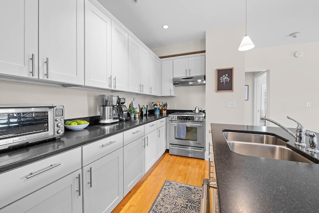 75 Clearwater Dr Unit 305, Falmouth, ME 04105 - kitchen featuring pendant lighting, stainless steel stove, a sink, under cabinet range hood, and white cabinetry