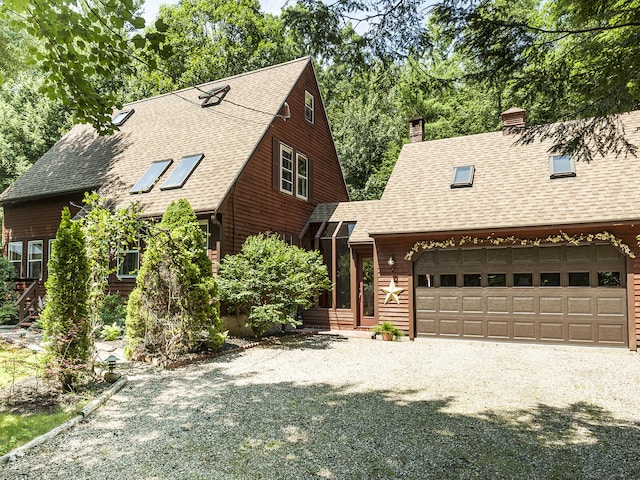 view of front of house with an attached garage, driveway, a shingled roof, and a chimney