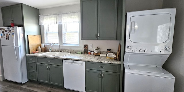 clothes washing area featuring laundry area, a sink, dark wood-style flooring, and stacked washing maching and dryer