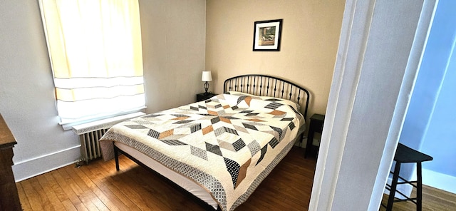 bedroom featuring baseboards, hardwood / wood-style flooring, and radiator