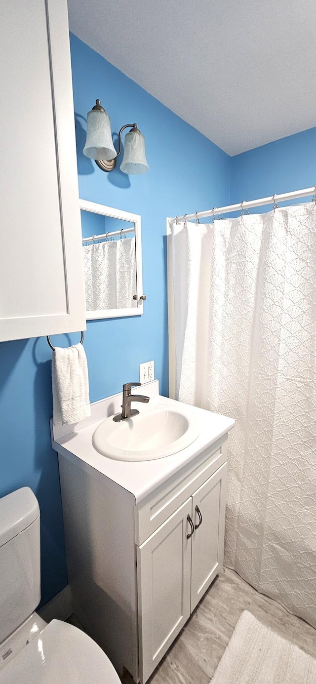 full bath featuring vanity, a shower with shower curtain, wood finished floors, and toilet