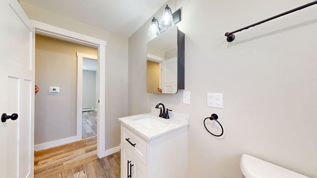 12 Marble Ln, Dixfield, ME 04224 - half bathroom featuring wood finished floors, toilet, vanity, baseboard heating, and baseboards