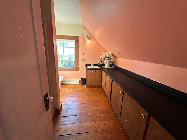 344 Main St, Lincoln, ME 04457 - bathroom featuring vanity, a baseboard radiator, toilet, lofted ceiling, and hardwood / wood-style floors