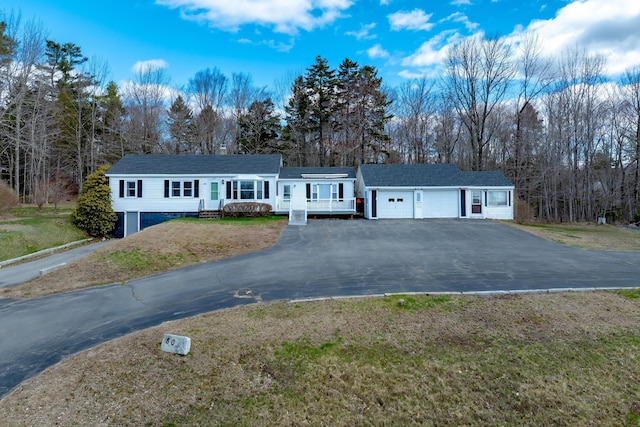 ranch-style house with covered porch, an attached garage, a front yard, and aphalt driveway