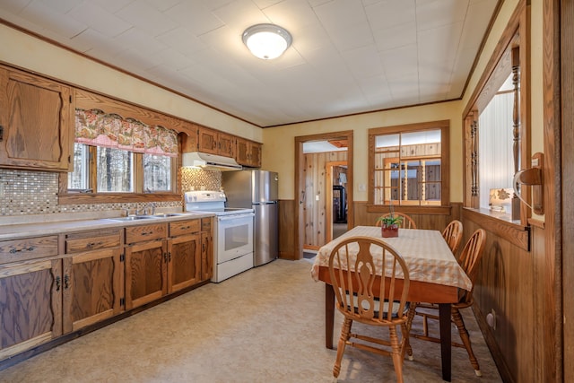 kitchen with decorative backsplash, electric range, brown cabinets, a sink, and freestanding refrigerator