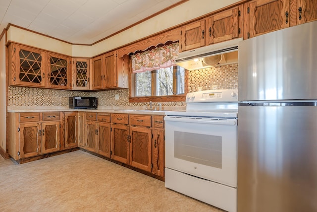 kitchen featuring freestanding refrigerator, white electric stove, brown cabinetry, and under cabinet range hood