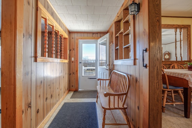 doorway with ornamental molding and wooden walls