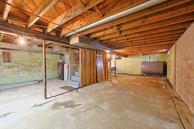 unfinished basement featuring heating fuel and stairs