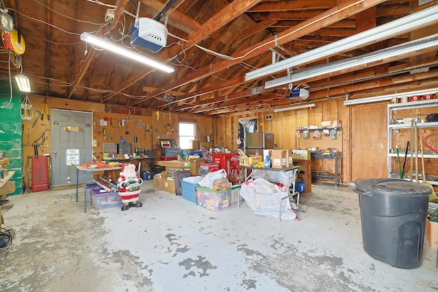 garage with a garage door opener, freestanding refrigerator, and a workshop area
