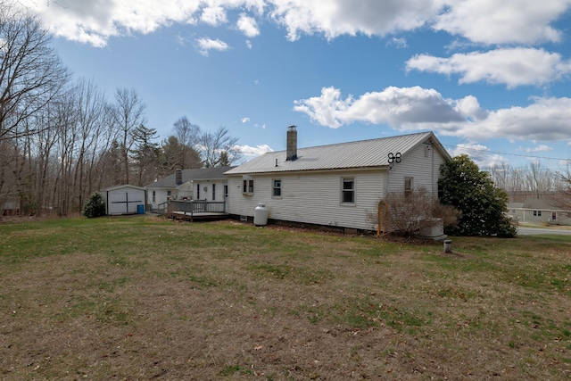 back of house with a storage shed, a wooden deck, an outbuilding, a chimney, and a yard