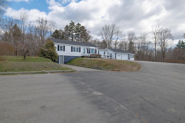 view of front facade with a garage, a front lawn, and driveway