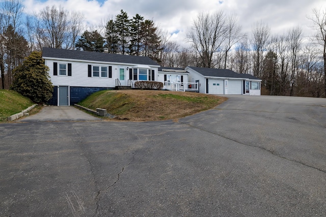 single story home with an attached garage, a front yard, and aphalt driveway