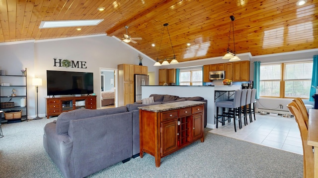 living area featuring light carpet, vaulted ceiling, wooden ceiling, a ceiling fan, and a skylight
