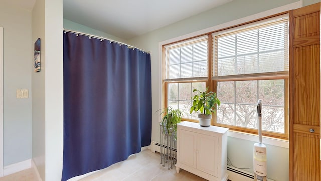bathroom with healthy amount of natural light, tile patterned flooring, baseboard heating, and vaulted ceiling
