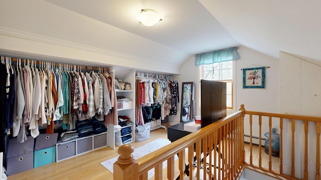 interior space with lofted ceiling, wood finished floors, and a baseboard heating unit