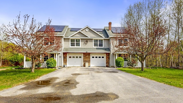 view of front of home featuring asphalt driveway, a front lawn, an attached garage, and a chimney