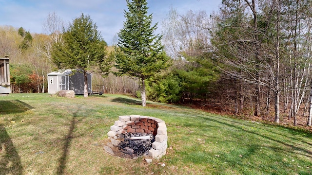 view of grassy yard with a storage unit, a fire pit, and an outbuilding