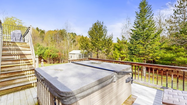 wooden deck featuring a hot tub, stairway, and an outbuilding