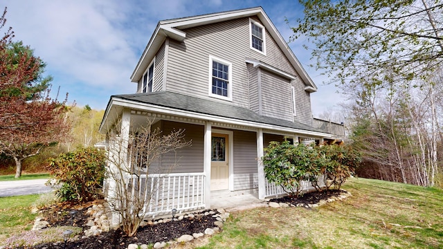 country-style home featuring a porch, roof with shingles, and a front yard