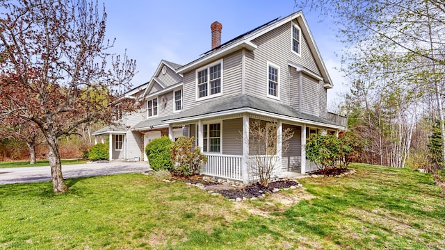 view of front of property featuring covered porch, driveway, a chimney, and a front lawn
