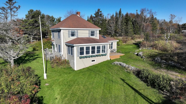 back of house featuring a lawn, roof with shingles, a wooden deck, and a chimney