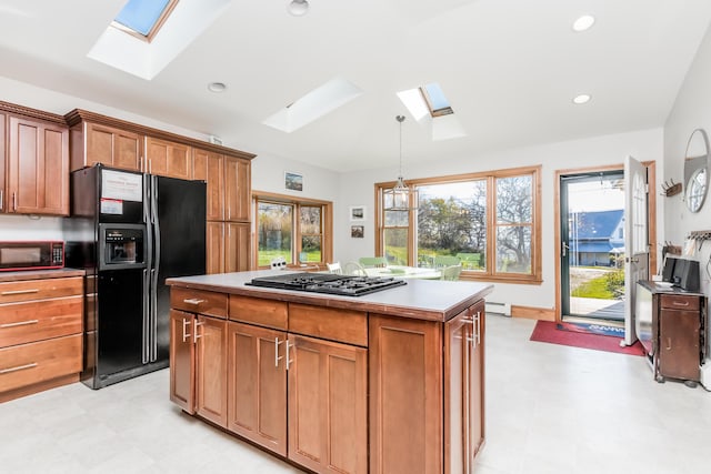 kitchen featuring stainless steel gas cooktop, a skylight, light floors, and black fridge with ice dispenser