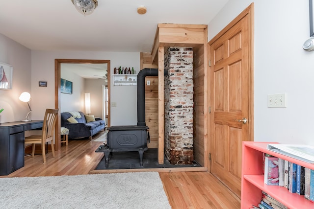 entrance foyer with a wood stove, ceiling fan, and wood finished floors