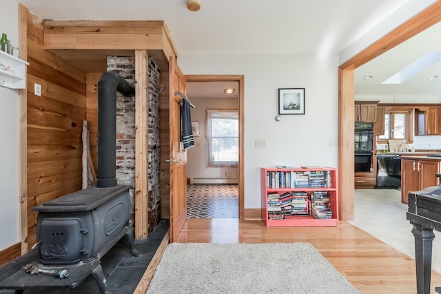 hall with light wood-style floors, a skylight, baseboard heating, and recessed lighting