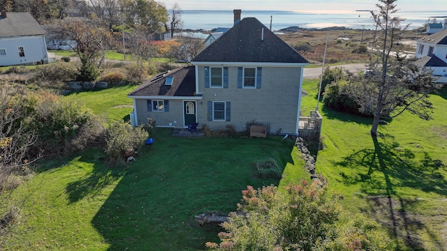 rear view of house featuring a lawn and roof with shingles
