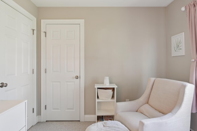 sitting room with baseboards and light colored carpet