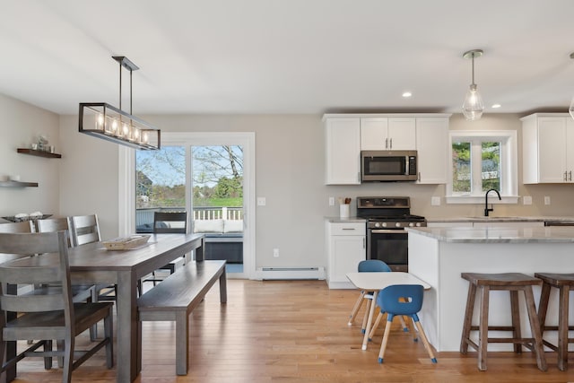 kitchen with a sink, appliances with stainless steel finishes, a baseboard radiator, and a healthy amount of sunlight