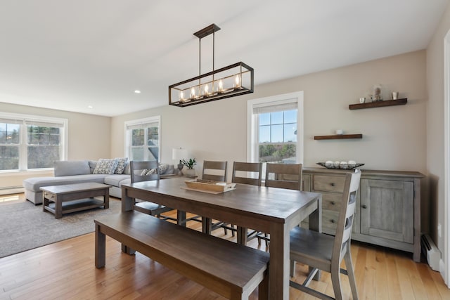 dining space with an inviting chandelier, a baseboard heating unit, recessed lighting, and light wood-style flooring