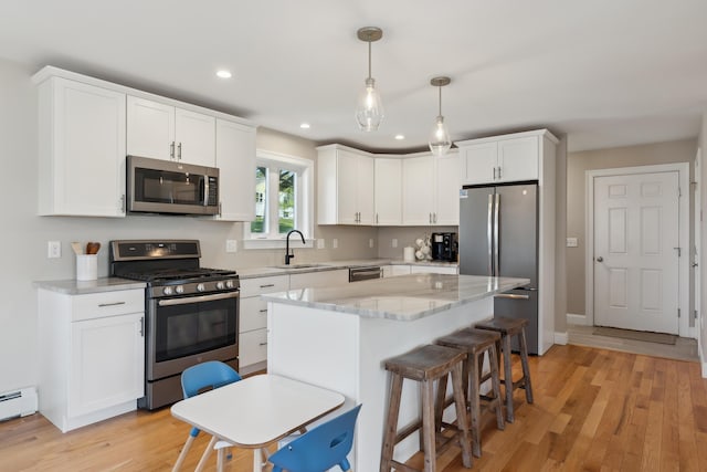 kitchen with white cabinets, appliances with stainless steel finishes, a sink, a breakfast bar area, and recessed lighting