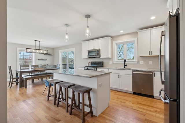 kitchen with white cabinets, stainless steel appliances, a sink, and a center island
