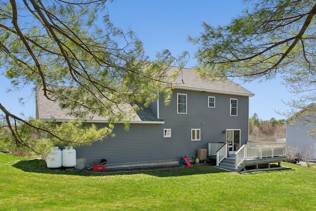 back of property with a lawn, roof with shingles, and a wooden deck