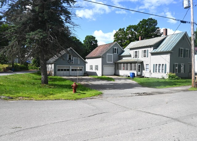 12 Preble St, Bingham, ME 04920 - view of front of house featuring a standing seam roof, a chimney, driveway, a front lawn, and a metal roof