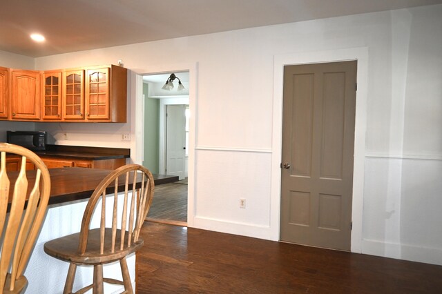 12 Preble St, Bingham, ME 04920 - kitchen with black microwave, dark wood-style flooring, glass insert cabinets, brown cabinetry, and dark countertops