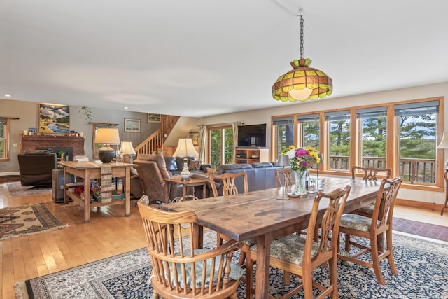 dining space featuring baseboards, stairs, a fireplace, and hardwood / wood-style flooring